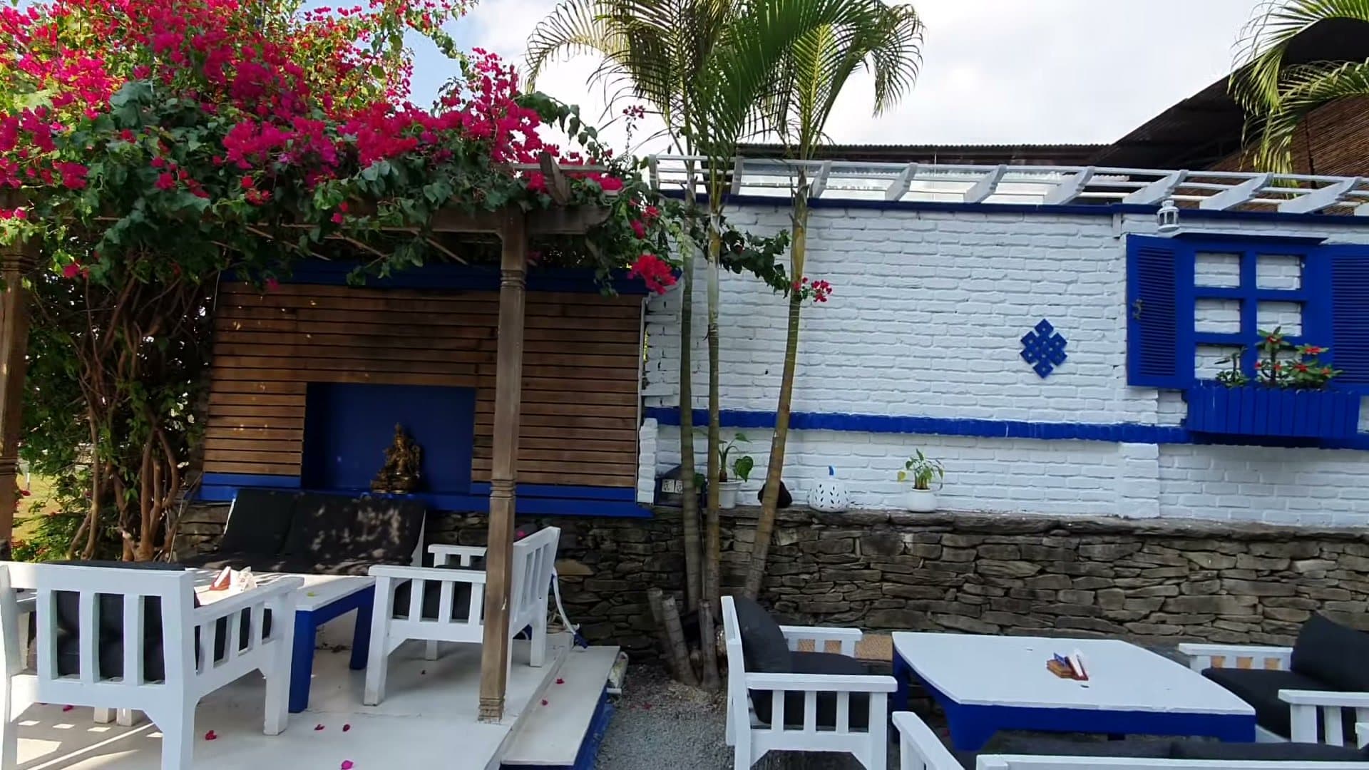 White brick courtyard with blue windows, stone wall and blue-and-white seating.