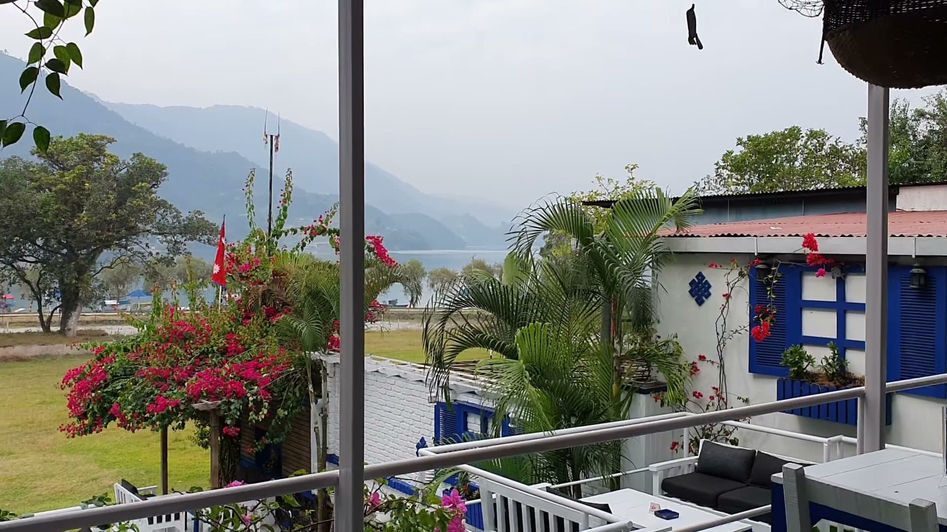 The upper terrace looking over palms and the lawn to Phewa Lake on a grey day.